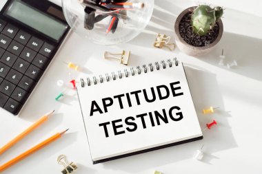 Beyaz bir ofis arkaplanı üzerinde yazıtlar APTITUDE TESTING ile not.