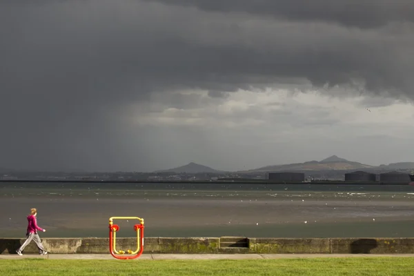 Frau spaziert entlang der Promenade in Clontarf mit Zuckerhut im Hintergrund — Stockfoto