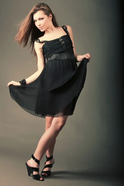 Beautiful girl in a black dress is dancing. — Stock Photo, Image