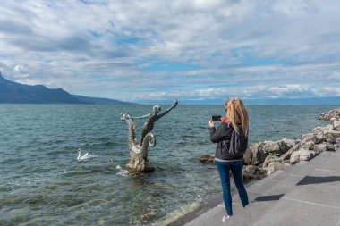 Vevey, İsviçre - 11 Ekim 2020: Sarışın kadın heykele fotoğraf çekiyor Edouard-Marcel Sandoz Vevey 'de, Cenevre Gölü, İsviçre