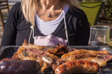 Arjantin barbeküsü ve arka planda odak dışı bir kadın.