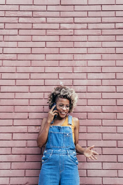 Cool musta Afrikkalainen amerikkalainen nainen vaaleat hiukset puhelun yli tiiliseinä — kuvapankkivalokuva