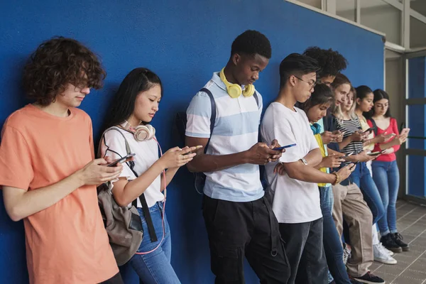 Gruppo di studenti adolescenti multirazziali che guardano i telefoni cellulari intelligenti durante le vacanze scolastiche - Concetto di dipendenza dai social media per problemi di nuova generazione — Foto Stock