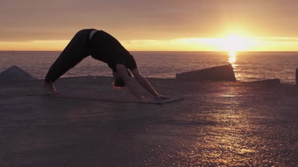 Adam gün doğumunda okyanus kıyısında vinyasa yogası yapıyor. — Stok video