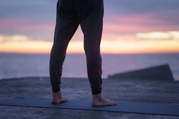 Lähikuva, jos mies jalat ja jalat seisoo jooga matta edessä meriveden aikaisin aamulla - Harjoitukset ja terve jooga Rutiini — kuvapankkivalokuva