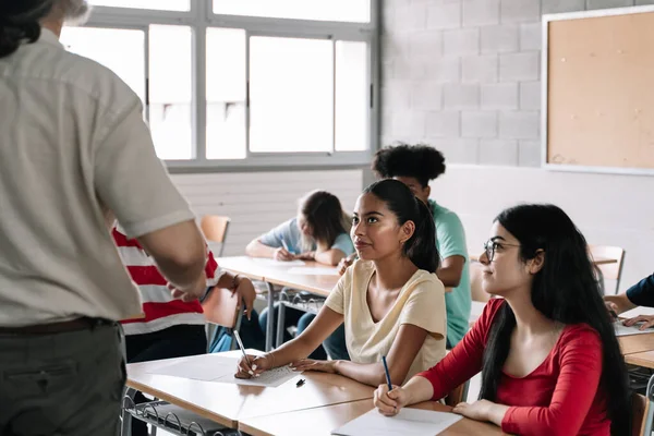 Іспаномовні та латиноамериканські студентки-підлітки уважно слухають пояснення вчителів у середній школі. Навчання й освіта в коледжі — стокове фото