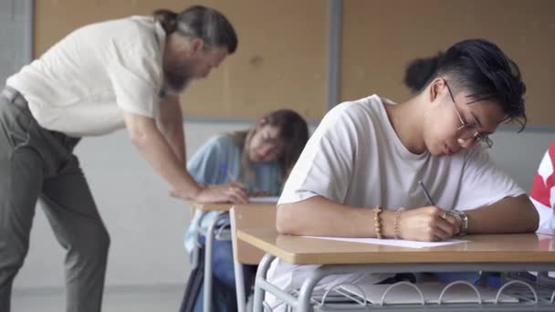 Asian Teenager Student bei der Prüfung. Hilfreicher Lehrer erklärt Schülern bei College-High-School-Test Übung — Stockvideo