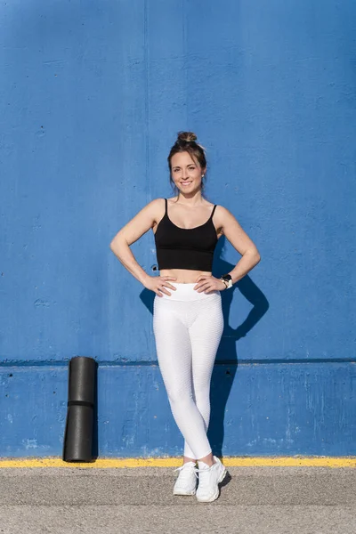 Junge Sportlerin mit Sportbekleidung über blauer Hintergrundwand bereit für Yoga und Fitnesstraining — Stockfoto