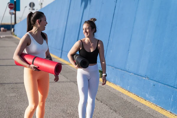 Atleet Vrouwen in fitnesskleding strekken zich uit over de blauwe wand, opwarmen voor de training — Stockfoto