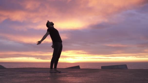 Mladý atletický muž vystupující za úsvitu na józe před oceánem. Zdravý duchovní ranní jóga rutina