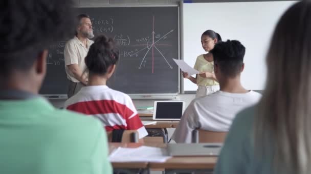 Studente delle scuole superiori latine che presenta un progetto o legge una composizione a compagni di classe e insegnanti. Ragazza nativa americana in classe — Video Stock