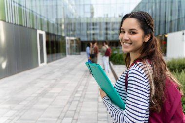 Genç Hispanik Üniversitesi Öğrenci Kadını Üniversite kampüsündeki derslere gidiyor. 