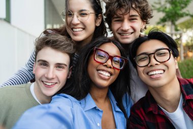 Üniversite öğrencisi arkadaşlar gülüyor, fotoğraf çekiyor, kaynaşıyorlar.