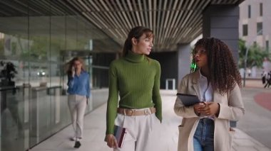 Mutlu bayan meslektaşlar ofis binasında yürüyor, sohbet ediyor, konuşuyor, iş projelerini tartışıyorlar. Çeşitlilik, iş kadınları