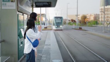 Şehir merkezindeki tramvayda bekleyen Asyalı turist çifti. Barselona 'da toplu taşıma yaşam tarzı