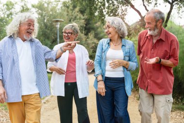 Şehir parkında gezen, gülen ve eğlenen mutlu bir arkadaş grubu.