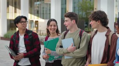 Bir grup üniversite öğrencisi ellerinde kitap ve kahkahalarla dersten sonra yürüyorlar.