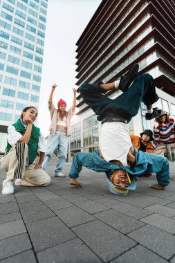 Afrikalı Amerikalı bir adam, şehirdeki çok kültürlü arkadaşlarıyla break dans yaparken eğleniyor.