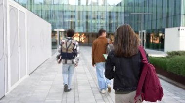 Kitapları olan Asyalı kız üniversite binasına yürüyor. Neşeli ve gülümseyen, ileriye bakan kameraya bakan