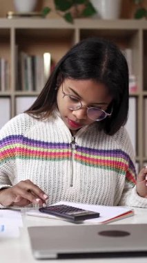 Gözlüklü, hesap makinesi kullanan ve evdeki Üniversite Sınavları için notlar yazan İspanyol kız.