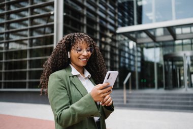 Modern Business District 'te cep telefonu kullanan ve kulak tıkacı takan genç bir kadın.