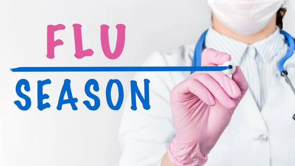 코트를 의사를 청진기와 분홍빛 장갑을 마커로 Flu Season 이라는 글자를 — 스톡 사진