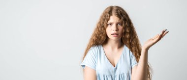 What the hell are you talking about, nonsense. Studio shot of frustrated female with curly long hairstyle gesturing with raised palm, frowning, being displeased and confused with dumb question.