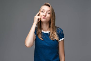 Stüdyoda kendine güvenen, düz sarı saçlı, mavi tişörtlü, başını işaret eden genç bir kadın var. Düşünce anlayışı. Akıllı ol ve düşün..