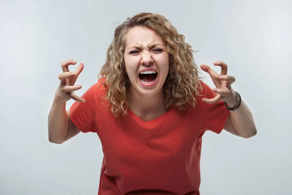 Öfkeli, kıvırcık saçlı, sıradan tişörtlü, bağıran ve öfkeyle el kaldıran sarışın kadın. Çığlık, nefret, öfke. Olumsuz duygu, yüz ifadesi konsepti. Stüdyo çekimi, beyaz arkaplan, izole edilmiş