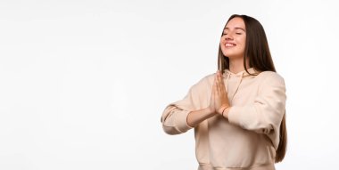 Uzun saçlı, mutlu esmer bir kadının resmi. Gülümseyen ve avuçlarını bir arada tutan sıradan kıyafetler giymiş bir kadın. Meditasyon yapıyor, barış ve sevgi için dua ediyor, sakin ve huzurlu bir yüz ifadesi var.