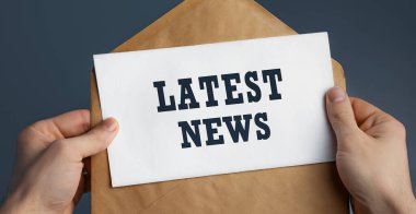 Mavi arka planda LATEST haberleri, iletişim konsepti içeren el sanatları zarfı tutan bir erkek.