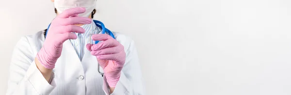 Cropped view of female doctor in a white coat, in a medical mask and pink sterile gloves holding ampoule vaccines. Concept: diseases, medical care, science, anesthesia, euthanasia, diabetes