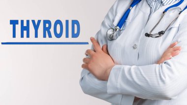 Beyaz bir arka planda kelime THYROID. Yakınlarda beyaz önlüklü ve steteskoplu bir doktor var. Tıbbi konsept