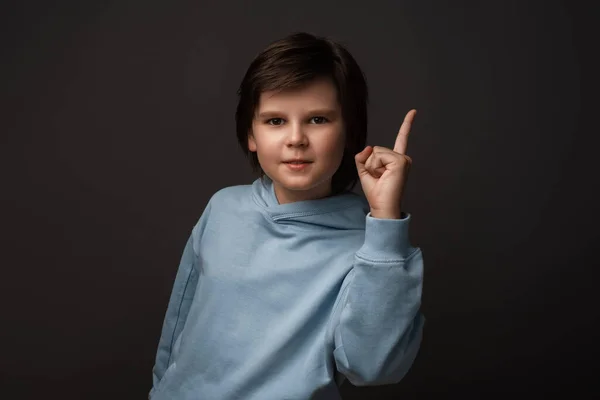 真剣な少年の肖像10 12歳のカジュアル服の人差し指を示すか 誰かを叱るか または伝える 小さな男の子が指を上げる と言う 注意してください スタジオ撮影 グレーの背景 — ストック写真