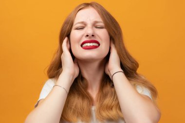 Uzun dalgalı sarı saçlı, beyaz tişörtlü, kulakları kulaklarla kaplı, elleri rahatsız edici bir ifadeyle yüksek sesli müzik sesi çıkaran güzel bir kız. Sağır kavramı.