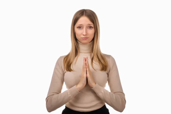Çekici sarışın kız gündelik giysiler içinde ailenin sağlığı için dua ediyor, dua etmek için avuç içlerini birbirine bastırıyor, namaste diyor. İnsani duygular, jest kavramı. Stüdyo çekimleri beyaz arkaplan