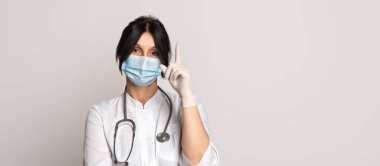 Ciddi kadın doktor portresi koruyucu yüz maskesi takıyor, işaret parmağı gösteriyor, diyor ki: Koru kendini. Tıp, meslek ve sağlık hizmetleri kavramı. İlan için yer