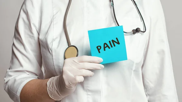 医生身穿白色外套 戴着无菌手套 手里拿着写有 Pain 字样的便条 医疗概念 — 图库照片