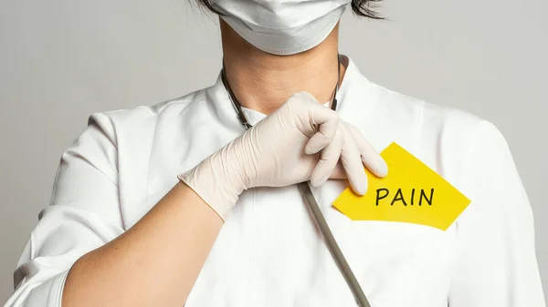 医生身穿白色外套 戴着无菌手套 手里拿着写有 Pain 字样的便条 医疗概念 — 图库照片