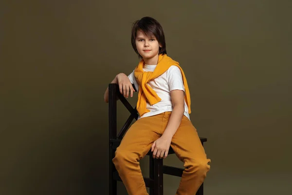 Όμορφο Αγόρι Της Μόδας Ετών Κάθεται Μια Καρέκλα Στο Στούντιο — Φωτογραφία Αρχείου
