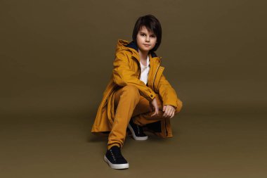 Stüdyoda yeşil arka planda poz veren 11-13 yaşlarında genç bir çocuğun portresi. Sıradan bir tarz. Stüdyoda şık bir çekim.