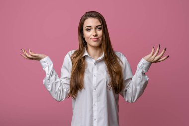 Bilmiyorum, bu ben değilim. Kafası karışık, şaşkın, pembe arka planı olan, elleri yana açık omuz silken, cahil ve kararsız esmer kızın portresi.