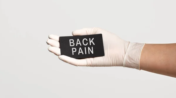 白い滅菌手袋の手の閉鎖は テキストでカードを保持 戻る痛み 医学的概念 — ストック写真