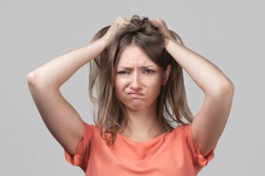 Panik içinde genç sarışın bir kadının korku ve hayal kırıklığı içinde başını tutuşu. Stres ve akıl sağlığı. Stüdyo çekimi, gri arkaplan