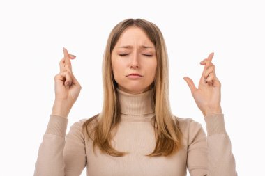 Sıradan elbiseli çekici sarışın kız şans dileyip dileğinin gerçekleşmesi için dua ediyor. İnsani duygular, jest kavramı. Stüdyo çekimi, beyaz arkaplan