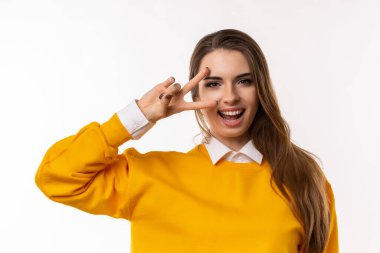 İyimser esmer bir kızın portresi, gözünün üzerinde barış işareti ve gülümseme, sana olumlu titreşimler gönderiyor, inancın tamamen iyi olması, beyaz arka plan. Sadece sakin ol.