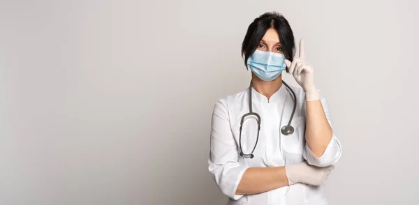 Ciddi kadın doktor portresi koruyucu yüz maskesi takıyor, işaret parmağı gösteriyor, diyor ki: Koru kendini. Tıp, meslek ve sağlık hizmetleri kavramı. İlan için yer