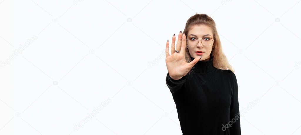blonde woman with long curly hair looking serious, stern, displeased and angry showing open palm making stop gesture. Studio shot, white background, isolated, gesture concept