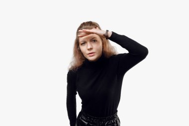 Meraklı siyah elbiseli genç bir kadının portresi. Alnına bakıp uzaklarda bir şeyler görmeye çalışıyor. Stüdyo çekimi, beyaz arkaplan