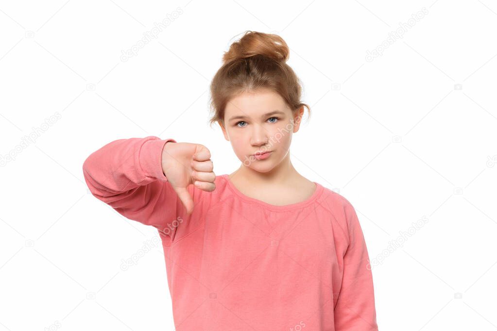 displeased teen girl isolated on white background showing thumb down with negative expression, gesture concept
